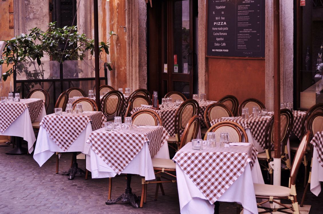 Outdoor restaurant tables with checked tablecloths in Rome.